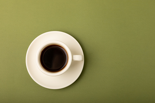 A cup of coffee on an olive background. Espresso. View from above. Space for copy.MOCAPS.