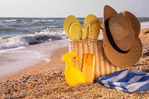 beach vacation concept. straw hat with beach bag and flip flops on the beach, with copy space.