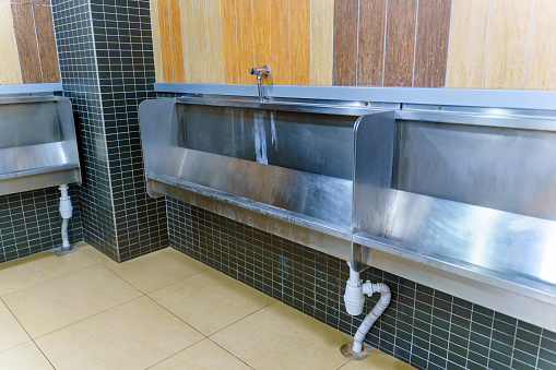 Collective grooved urinal made of metal in a public toilet
