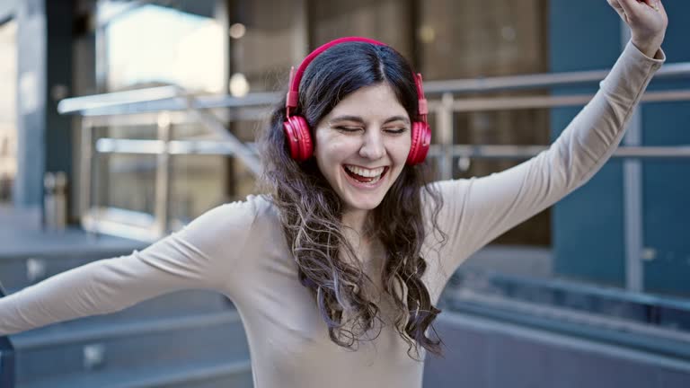 Young beautiful hispanic woman smiling confident listening to music dancing at street