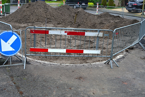 Leuven, Vlaams-Brabant, Belgium -May 10, 2023: white and red barrier fences in front of an excavated hole to transform asphalt street in a square park in permeable surface materials
