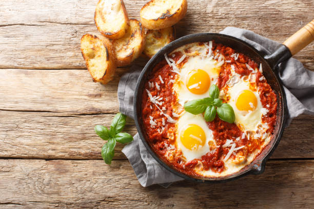 Eggs in Purgatory is a delicious Southern Italian dish consisting of fried eggs in a spicy tomato sauce with onions and garlic closeup on the skillet. Horizontal top view stock photo