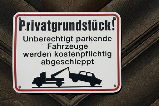 Sign with German inscription Privatgrundstück, parkende Autos werden abgeschleppt. Translation: private property, parked cars will be towed away for a fee