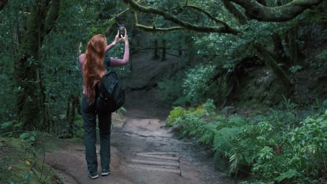 Woman is in an enchanted forest taking a selfie.