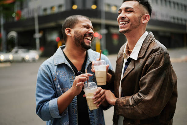게이 친구들은 아이스 커피를 마시고 도시의 보도에서 웃고 있다 - gay man couple lifestyles homosexual 뉴스 사진 이미지
