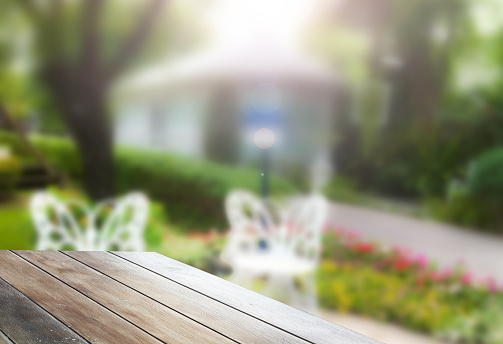 Wooden table with blurred gazebo in the garden. For product display advertising background. Empty table top for promote restaurant or cafe. Copy space for garden cafe idea.