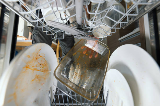 putting dirty greasy dishes into dishwasher. inside view stock photo