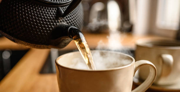 istock Pouring hot black tea from metal teapot 1488929515