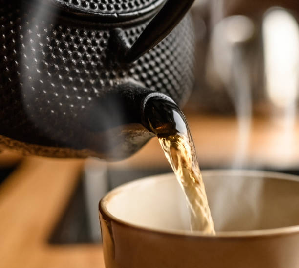 istock Pouring hot black tea from metal teapot 1488929543