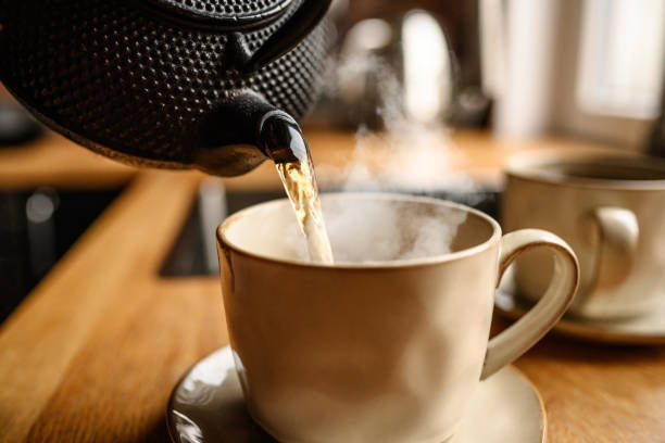 istock Pouring hot black tea from metal teapot 1488929569