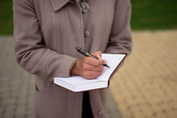 istock A black woman in a coat makes a note in a notebook standing on the street. 1488930168