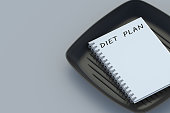 Inscription diet plan on notepad near fry pan. Healthy eating. Calorie control. Nutritionist consultation. Meal schedule. Slimming concept. Copy space. 3d render slimming