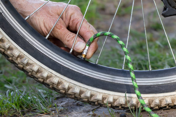 homem bombeando roda de bicicleta no parque. homem infla roda de bicicleta usando uma bomba. - bicycle bicycle pump inflating tire - fotografias e filmes do acervo