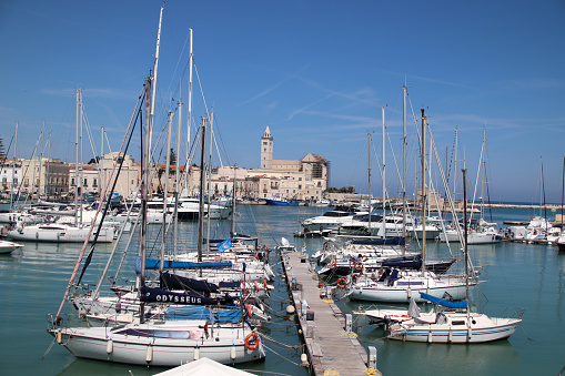 Trani, Province of Barletta-Andria-Trani, Italy - 7 may 2023: the port, with the municipal dock, the Cathedral of San Nicola Pellegrino, with the apse under restoration, and the church of Santa Teresa