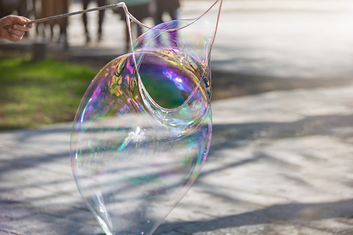 A man makes a huge soap bubble in the park. Summer fun in the park for the whole family. High quality photo