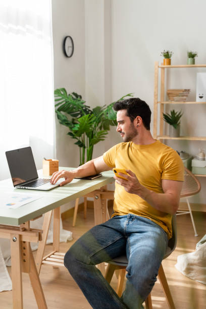 istock Casual man using laptop at home desk. 1488937195