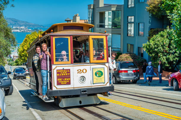 People ride cable car in San Francisco, California, USA on a sunny day.