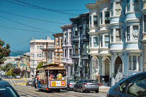People ride cable car in San Francisco, California, USA on a sunny day.