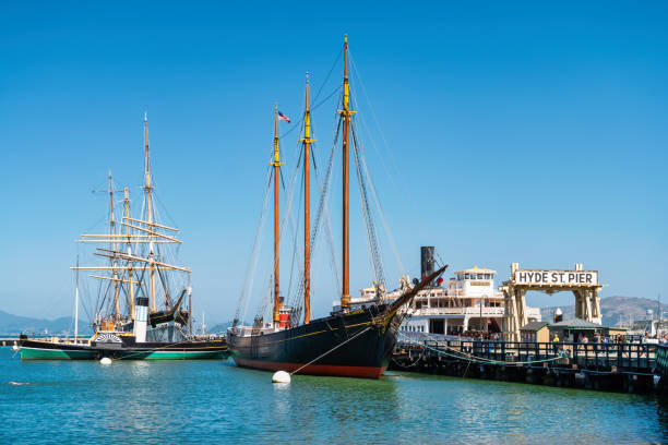 People walk at the Hyde Street Pier Historic Ships in San Francisco, California, USA on a sunny day.
