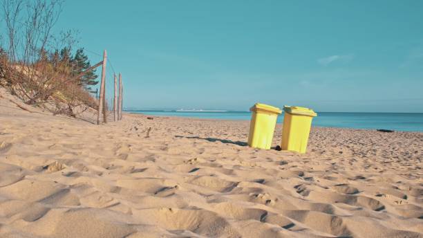 istock Yellow Plastic Dumpster Bins on Seashore Beach for Collecting Garbage during Summer Vacation Season 1488942894