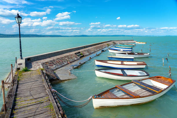 발라톤 호수의 화려한 보트가 있는 발라톤렐의 나무 부두, 푸른 하늘과 물 - pier rowboat fishing wood 뉴스 사진 이미지