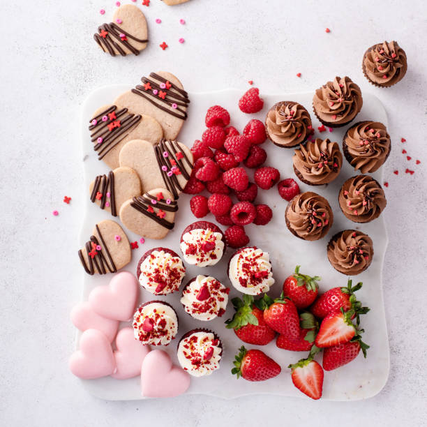 Valentines day charcuterie board or dessert snack board with cupcakes, cookies and strawberries