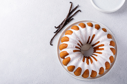 Vanilla bundt cake drizzled with powder sugar glaze with vanilla beans overhead view with copy space