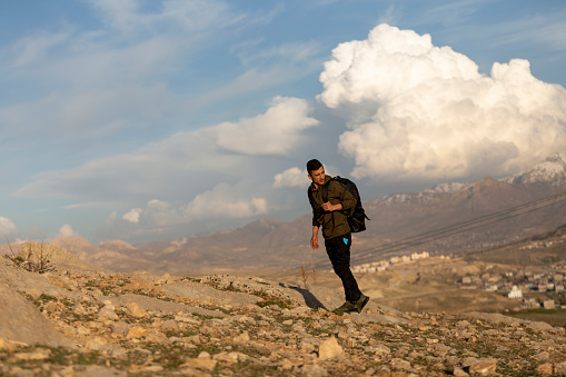 Male athlete hiking in mountainous area with backpack. Climbing the mountains in the Anatolian steppes. Wandering in the wilderness with a backpack.