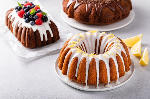 Variety of bundt cakes on the table with lemon, chocolate and berry cakes