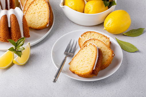 Lemon bundt cake drizzled with powdered sugar glaze topped with lemon zest sliced