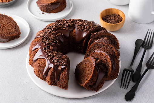 Chocolate cake baked in a bundt pan with chocolate ganache glaze and chocolate curls sliced