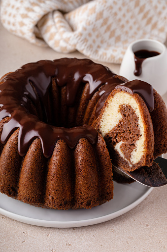 Chocolate marble bundt cake or zebra cake with chocolate glaze drizzled on top with a slice taken out