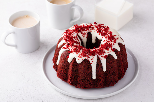 Red velvet bundt cake with cream cheese frosting and cake crumbs on top