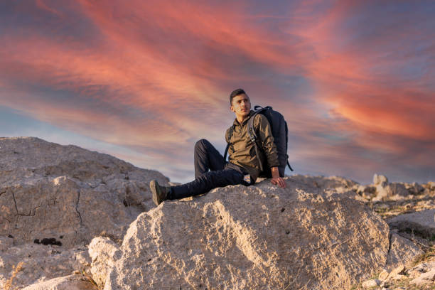 Mountaineer with a backpack. Young man treeking. Sunset.