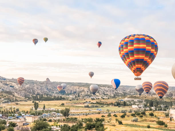 volare nel cielo molti bellissimi palloncini colorati in aria in cappadocia in montagna presto all'alba, all'alba. palloncino di riempimento con aria calda dal bruciatore, grande cestello. escursione turistica, volo nuvola - cappadocia hot air balloon turkey basket foto e immagini stock