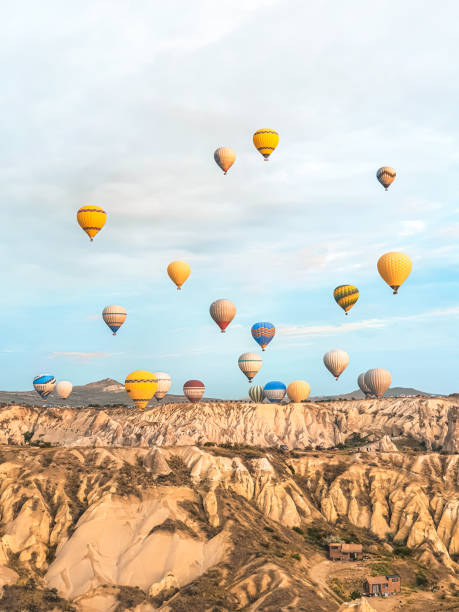 volare nel cielo molti bellissimi palloncini colorati in aria in cappadocia in montagna presto all'alba, all'alba. palloncino di riempimento con aria calda dal bruciatore, grande cestello. escursione turistica, volo nuvola - cappadocia hot air balloon turkey basket foto e immagini stock