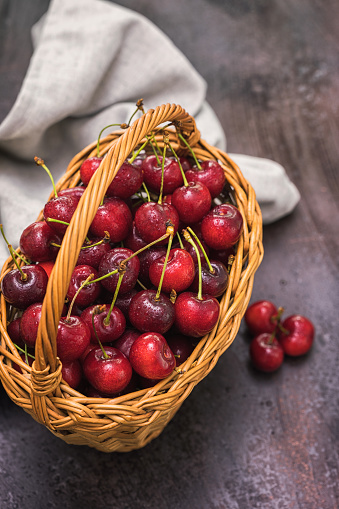 Fresh sweet cherries with water drops in a basket on a rustic background