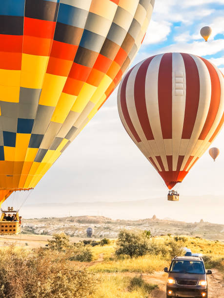 volare nel cielo molti bellissimi palloncini colorati in aria in cappadocia in montagna presto all'alba, all'alba. palloncino di riempimento con aria calda dal bruciatore, grande cestello. escursione turistica, volo nuvola - cappadocia hot air balloon turkey basket foto e immagini stock