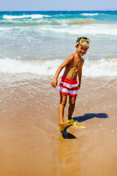 istock Smiling boy with scuba gear entering the sea 1488950581