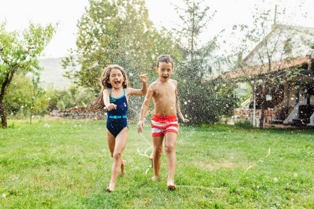 istock Children having fun refreshing with garden sprinkler 1488954623