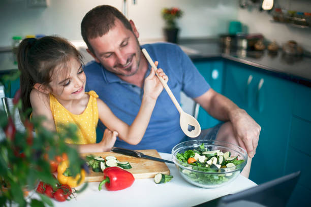 istock Father and daughter having fun and making salad together 1488954781