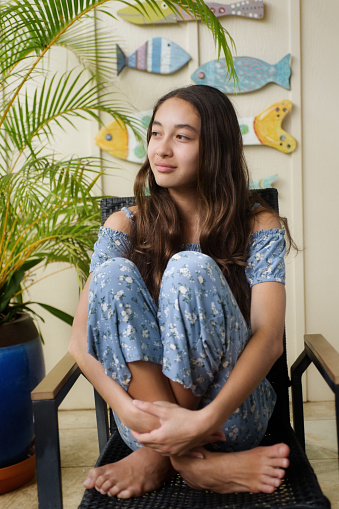 A young Hawaiian teen adolescent girl in her home, looking away