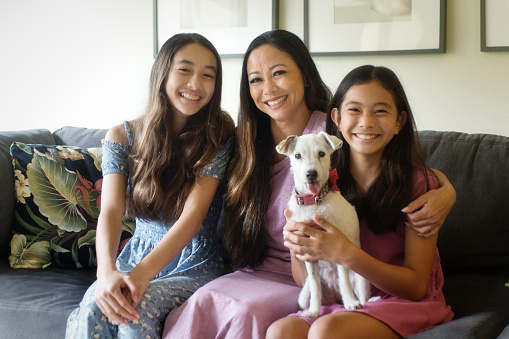Family portrait of a Hawaiian family, with mother and two teen girls, and family pet dog in their home