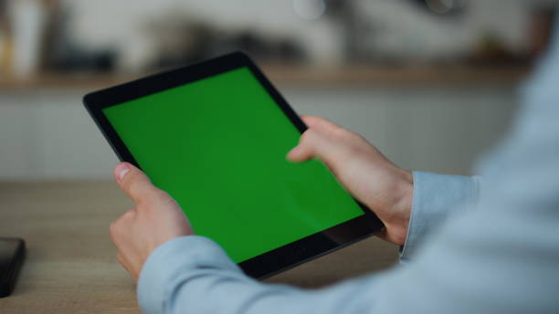 istock Hands touching greenscreen tablet searching information sitting at table closeup 1488956887