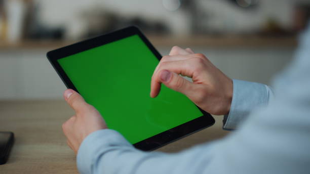 istock Hands holding mockup tablet close up. Guy touching green screen swiping zooming. 1488957496