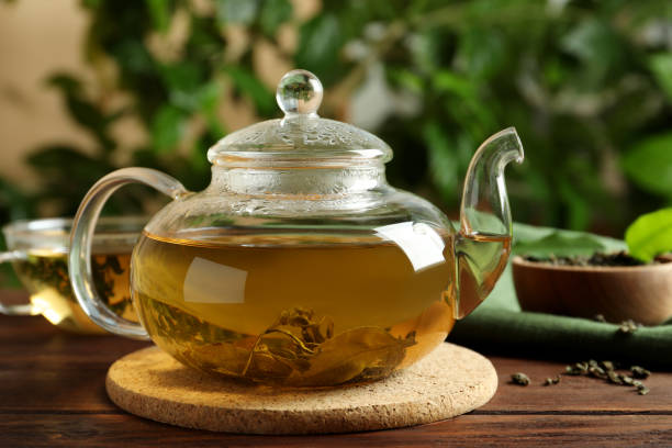 istock Glass teapot with fresh green tea on wooden table 1488957826