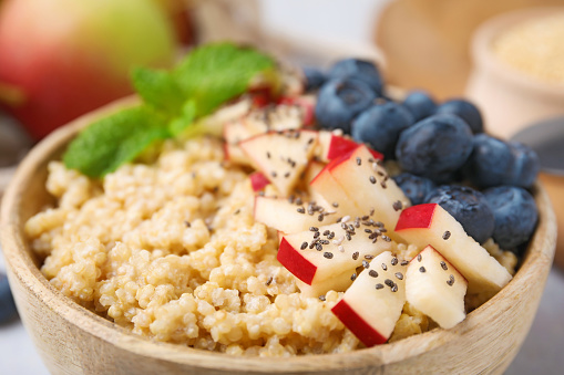 Bowl of delicious cooked quinoa with apples, blueberries and chia seeds, closeup