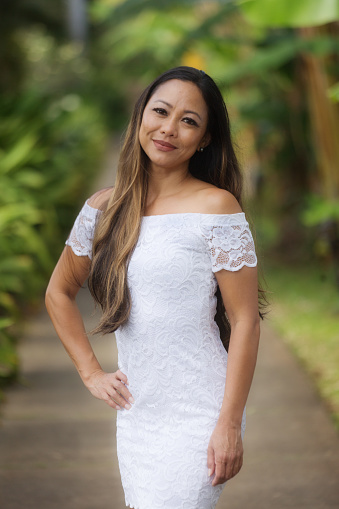 A Hawaiian woman in formal white dress, Smiling posing and looking at camera