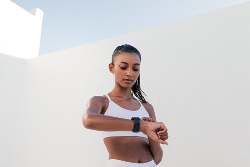 Slim female checking pulse on a smartwatch. Fitness influencer checking heart rate.