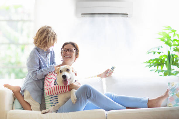 Mother and child with air conditioner remote Mother and child with air conditioner remote control. Comfortable temperature at family home. Cooling and heating device. Mom and kid on couch under cold breeze. Air conditioning on hot summer day. air conditioner family stock pictures, royalty-free photos & images